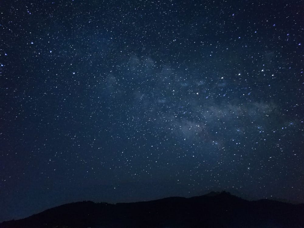 the night sky is filled with stars above a mountain